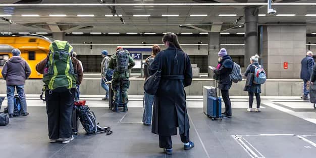 A group of passengers with luggage waiting on a railway station platform